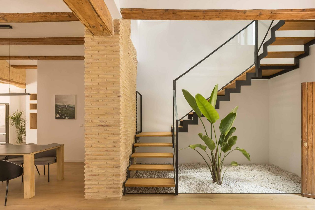 Rehabilitación y reforma Casa A_M Puzol Valencia - Escalera de nueva construccion con zanca metálica y espacio de jardin con grava blanca en el centro