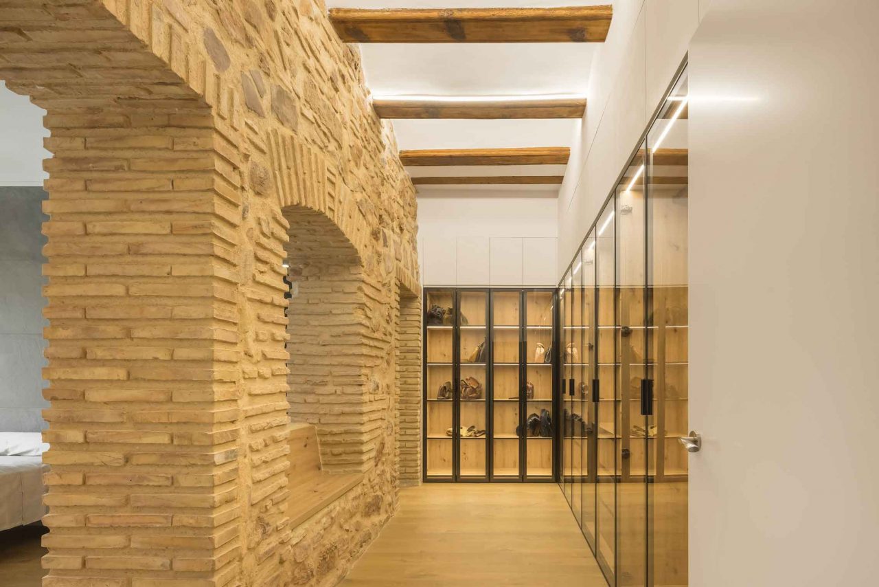 Rehabilitación y reforma -Casa-A_M-Puzol-Valencia---Vestidor-del-dormitorio-principal-con-puertas-de-vidrio-y-muro-de-piedra-de-la-fachada-original-restaurado
