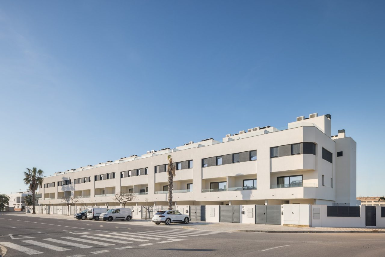 promoción residencial de 37 viviendas con fachadas blancas y grises cerca de la playa